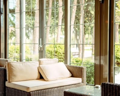 Wicker sofa by glass doors in sunroom.